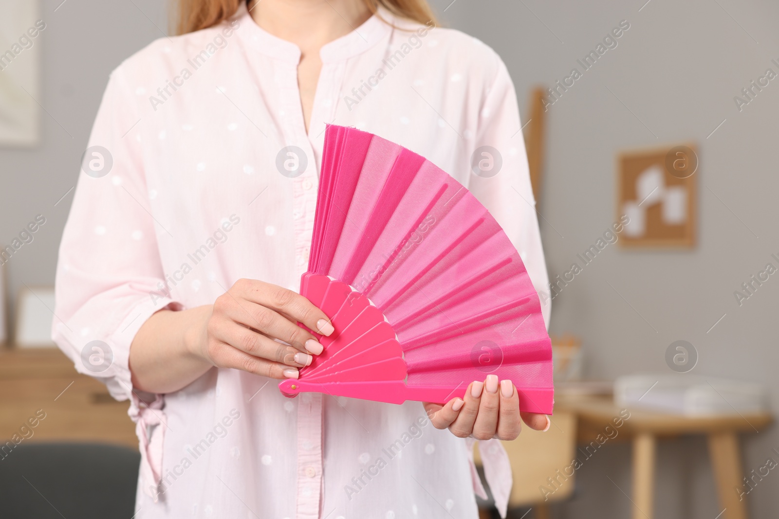 Photo of Woman with pink hand fan at home, closeup