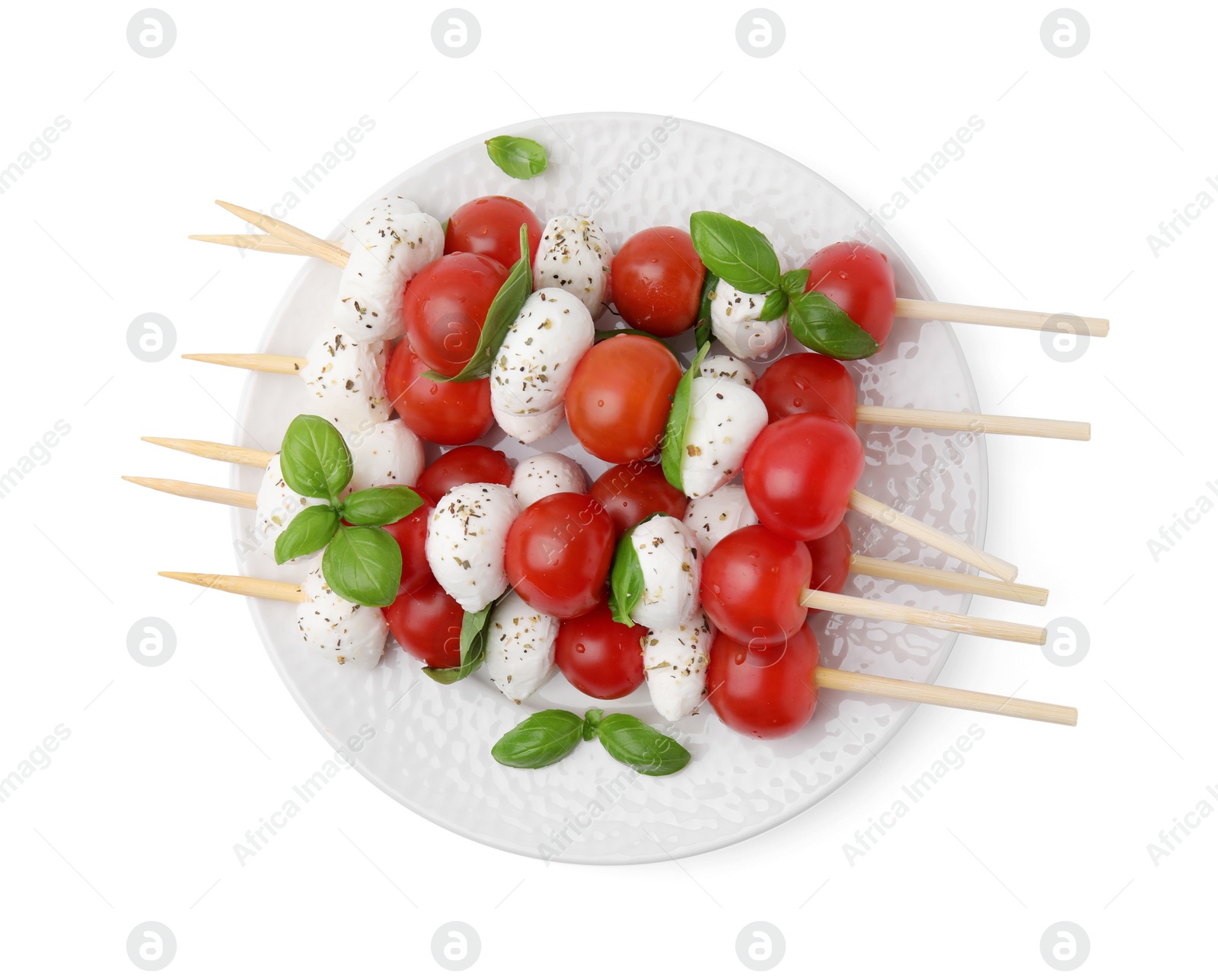 Photo of Plate of Caprese skewers with tomatoes, mozzarella balls, basil and spices isolated on white, top view