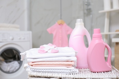 Bottles of detergent and children's clothes on wicker basket in bathroom