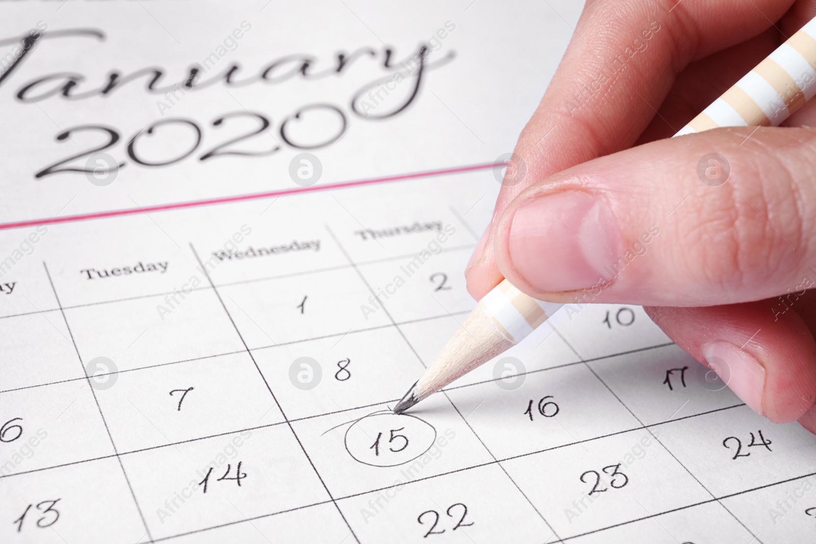 Photo of Woman marking date in calendar with pencil, closeup