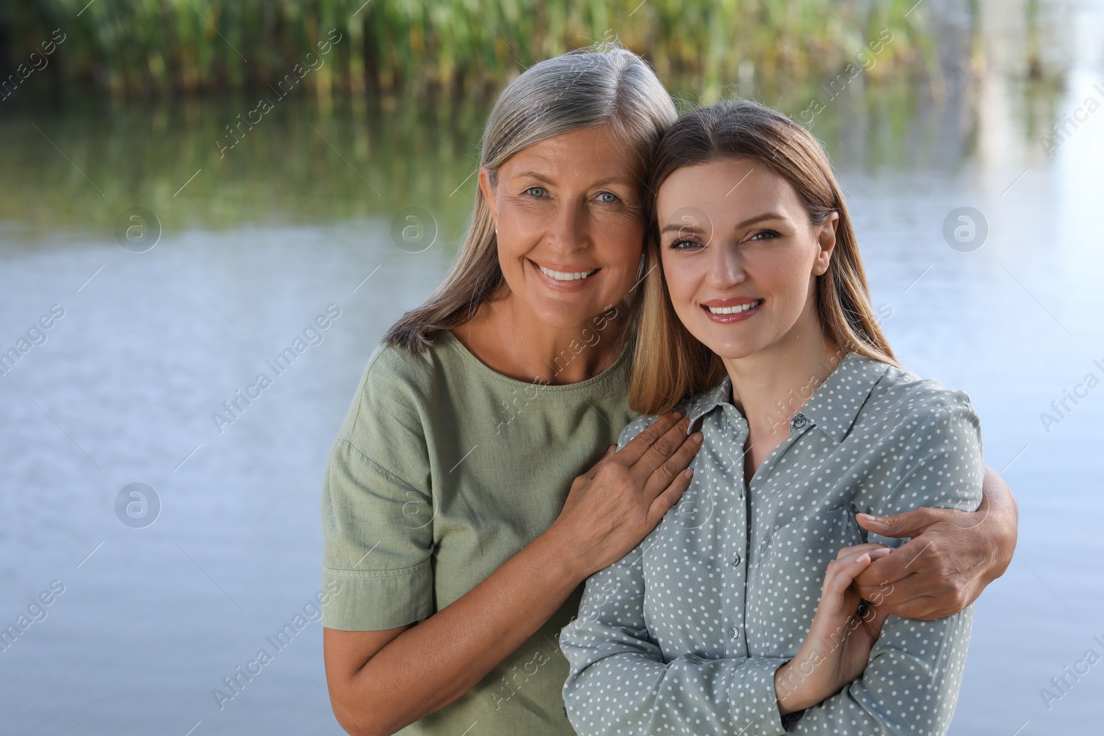 Photo of Family portrait of happy mother and daughter spending time together near pond. Space for text