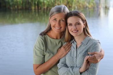 Family portrait of happy mother and daughter spending time together near pond. Space for text