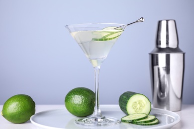 Composition with glass of cucumber martini on table against color background, space for text