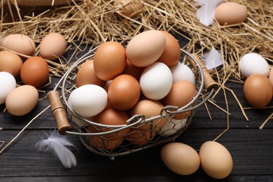 Fresh chicken eggs and dried straw on black wooden table