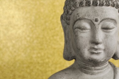 Photo of Buddha statue on golden background, closeup. Space for text