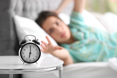 Photo of Alarm clock on table and woman in bedroom. Sleeping time