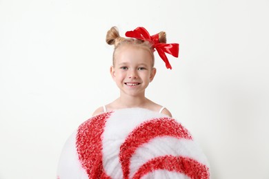 Cute little girl dressed as candy on white background. Christmas suit