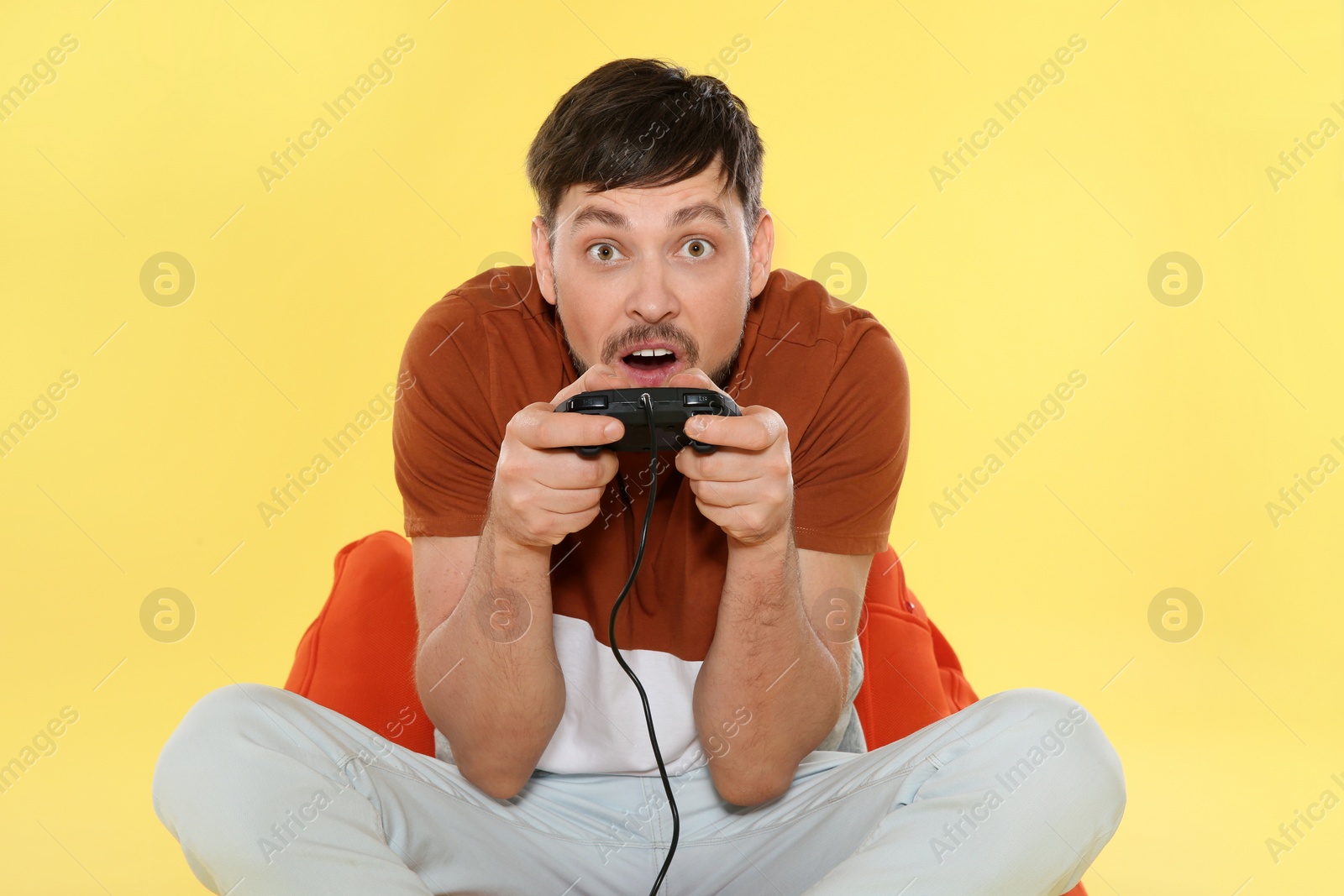 Photo of Emotional man playing video games with controller on color background