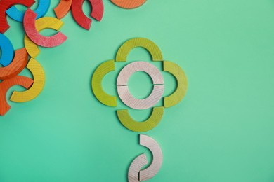 Photo of Colorful wooden pieces of play set on green background, flat lay. Educational toy for motor skills development