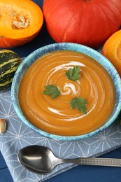 Photo of Delicious pumpkin soup served on blue wooden table