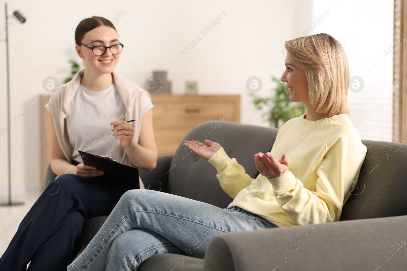 Photo of Professional psychotherapist working with on sofa patient in office