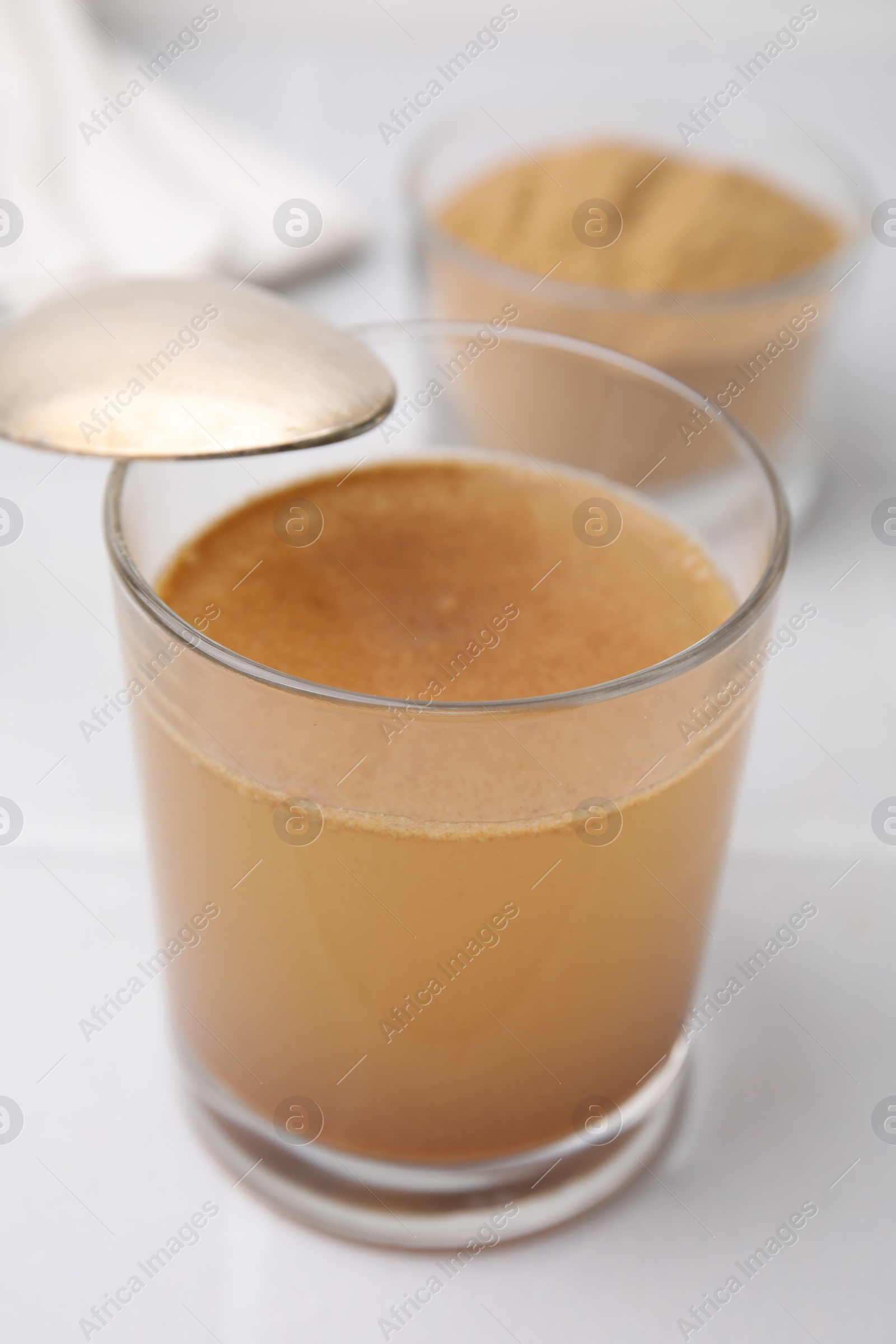 Photo of Soluble fiber with water in glass and powder on white table, closeup
