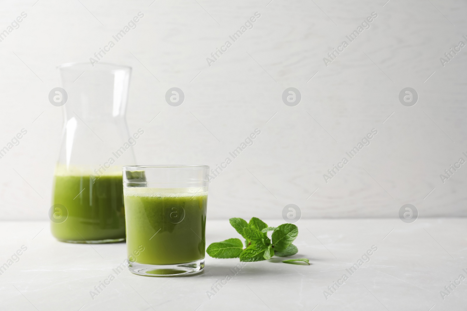 Photo of Glassware with delicious detox juice and mint on table