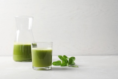 Glassware with delicious detox juice and mint on table