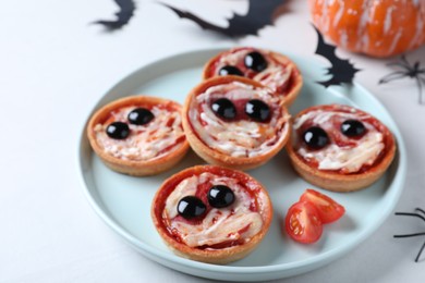 Photo of Cute monster tartlets served on white table. Halloween party food