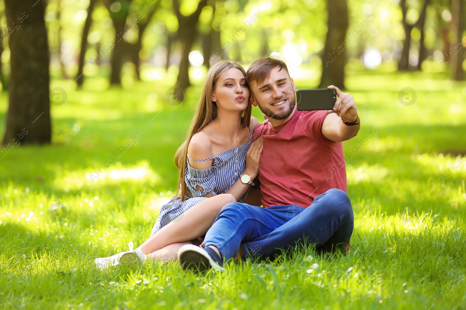 Photo of Happy young couple taking selfie on green grass in park