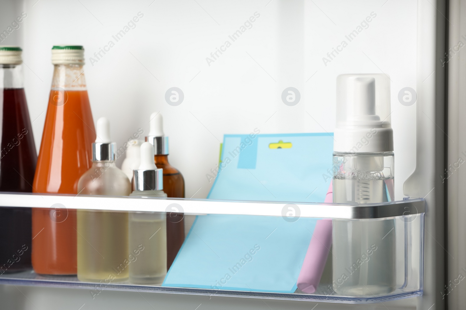 Photo of Different cosmetic products on shelf in refrigerator