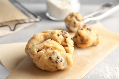 Photo of Raw cookie dough with chocolate chips on table, closeup