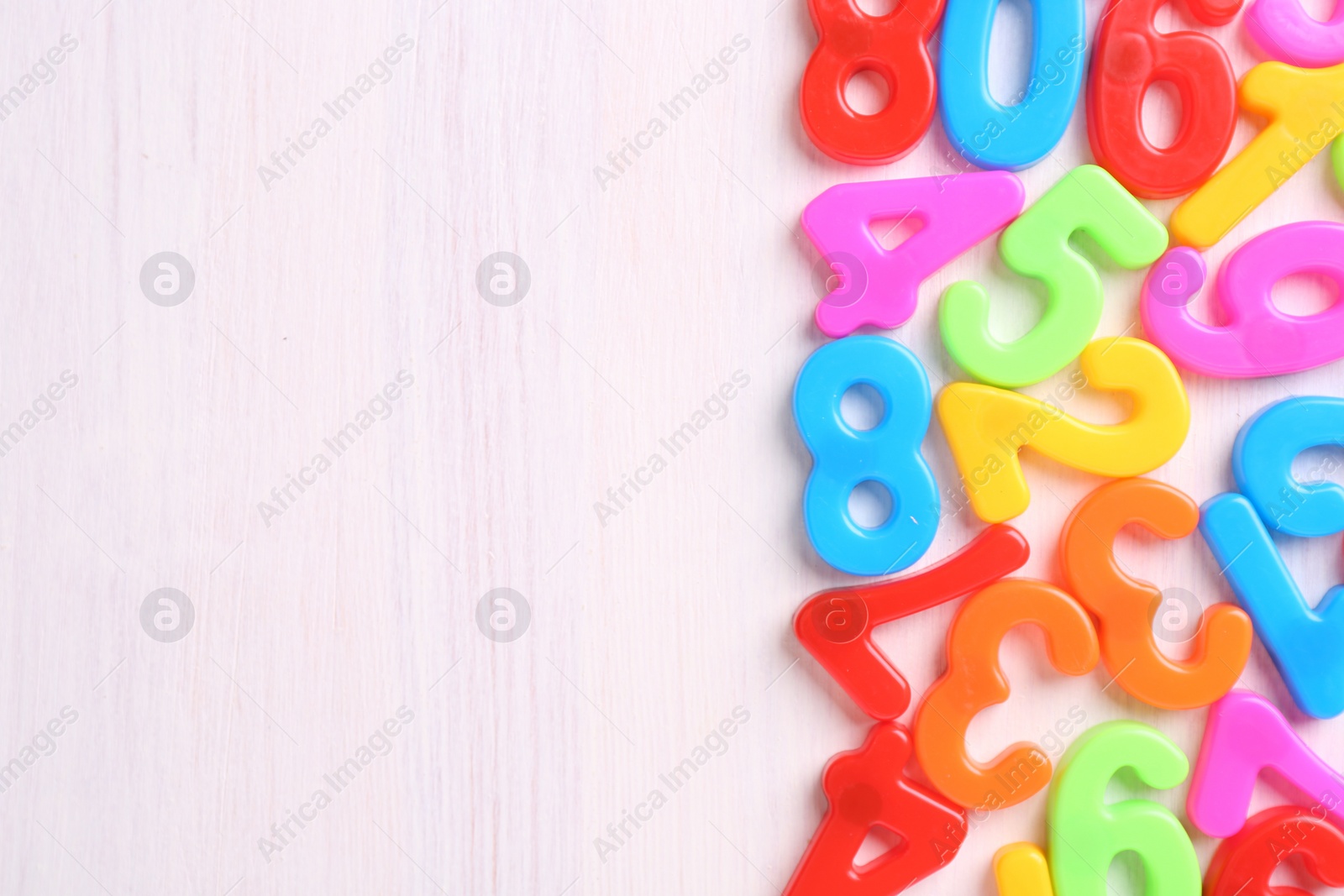 Photo of Colorful numbers on white wooden school desk, flat lay. Space for text