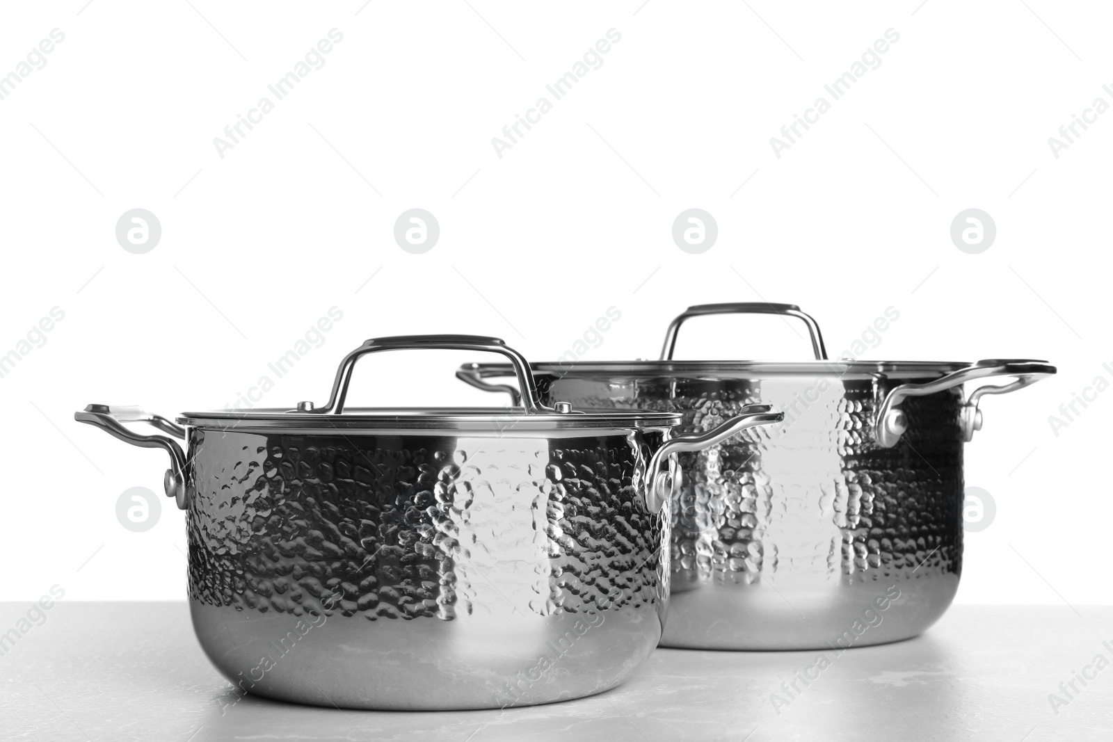 Photo of New clean saucepans on table against white background