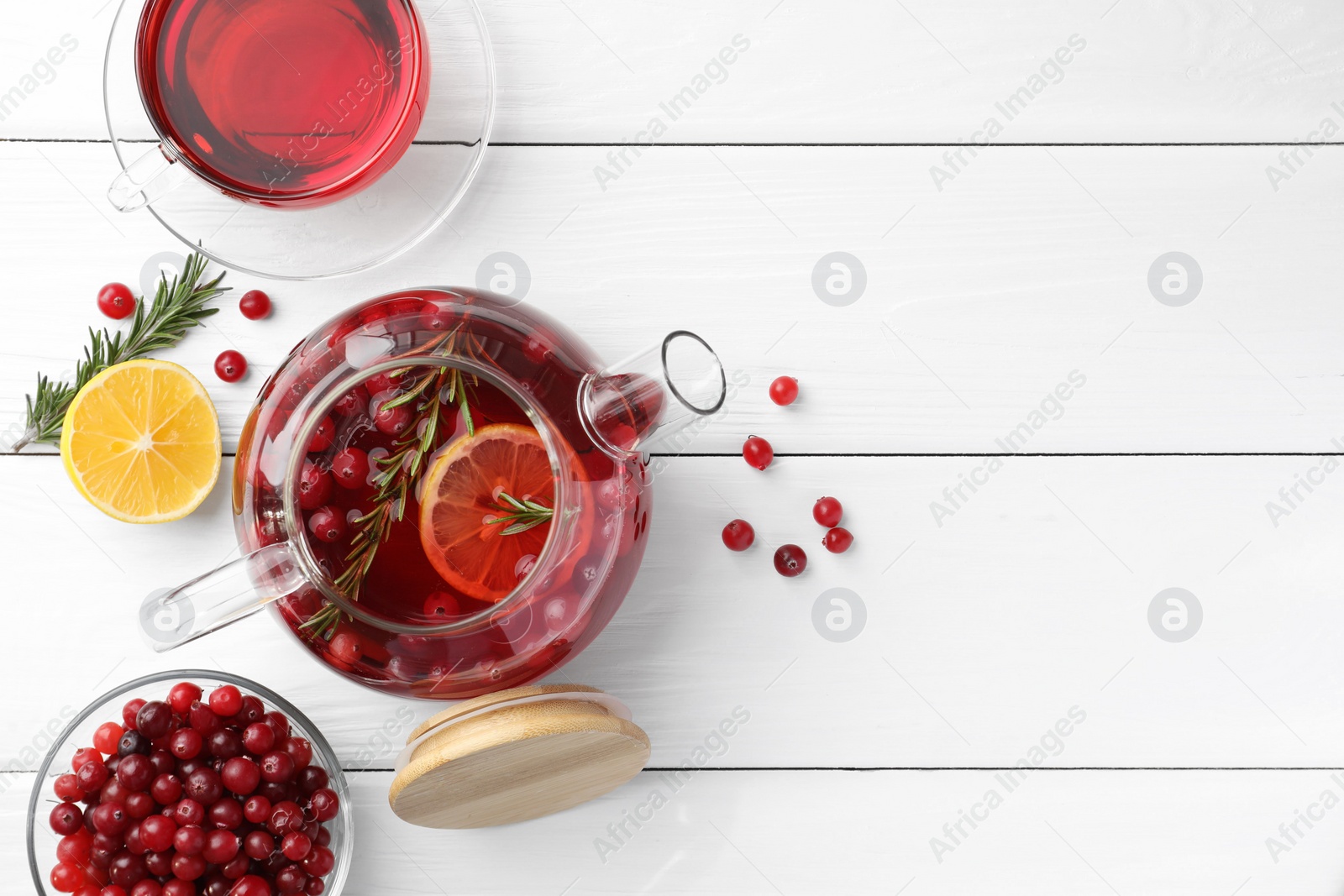 Photo of Tasty hot cranberry tea with lemon, rosemary and fresh berries on white wooden table