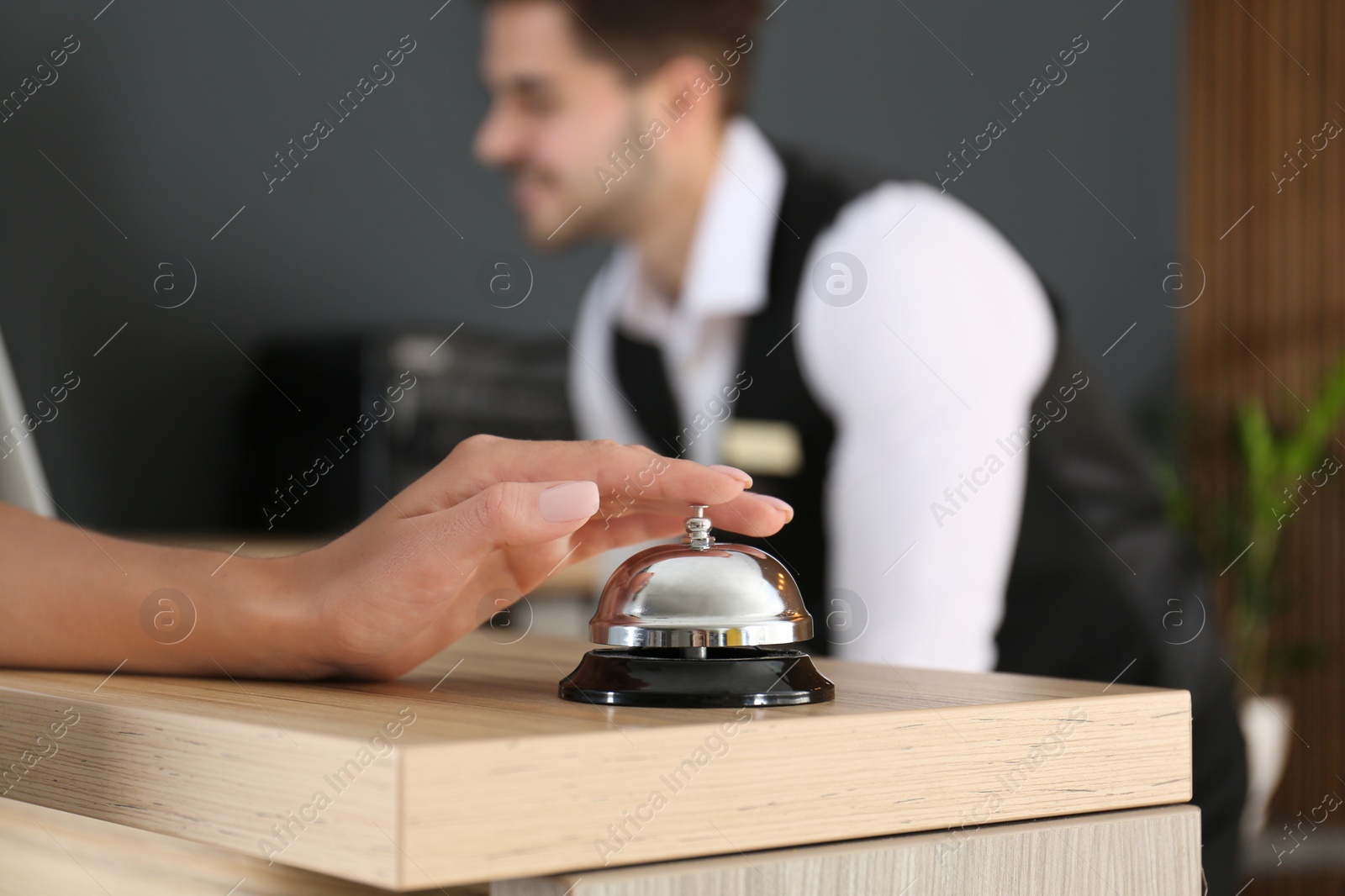 Photo of Woman ringing in bell on reception desk, closeup