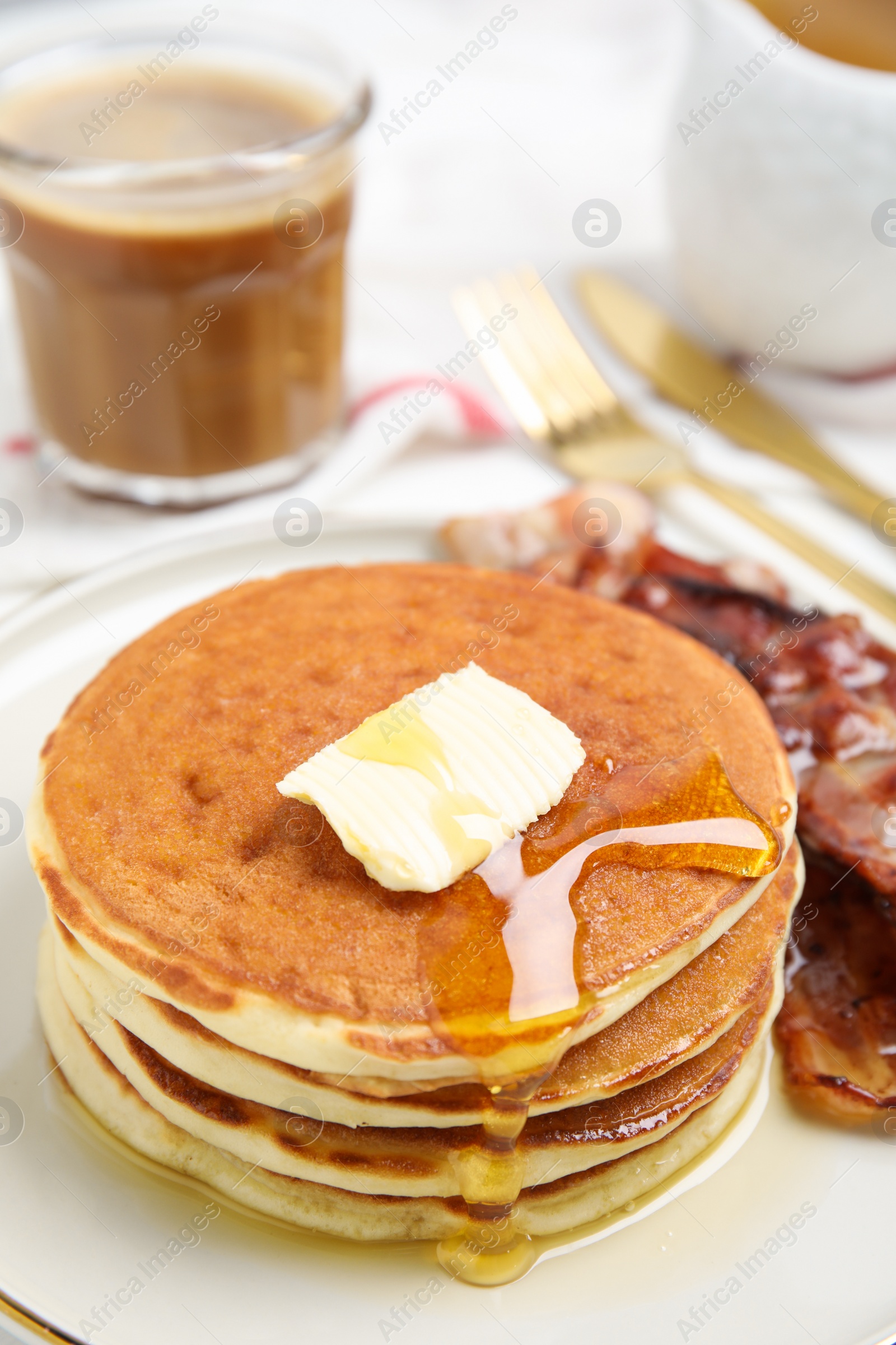 Photo of Delicious pancakes with maple syrup, butter and fried bacon on plate, closeup