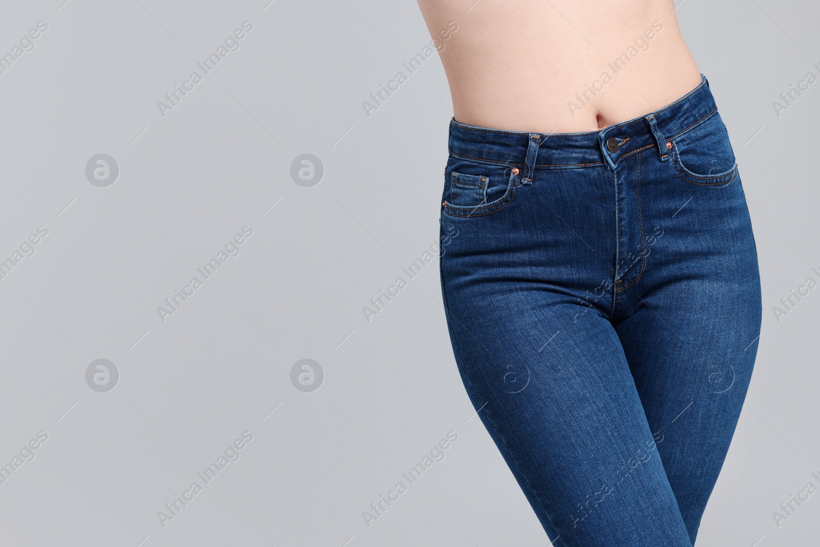 Photo of Woman in stylish jeans on grey background, closeup. Space for text