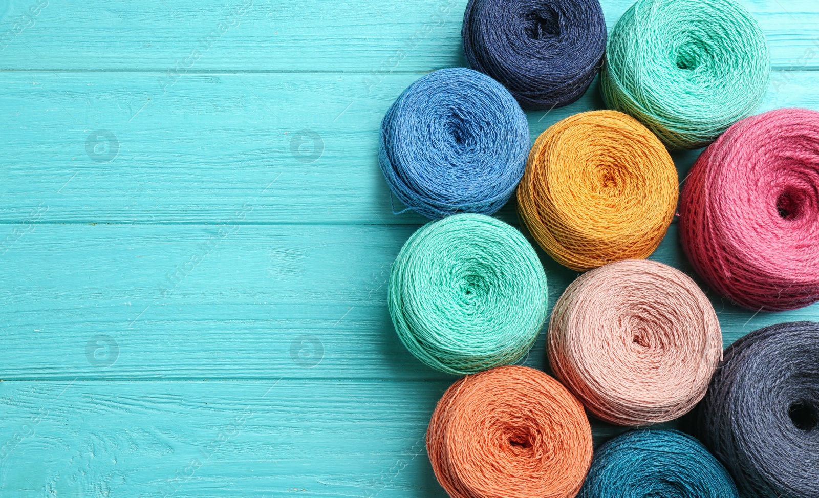 Photo of Colorful clews of threads on wooden table, top view. Space for text