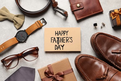 Photo of Card with phrase Happy Father's Day, shoes, gift boxes and men accessories on light grey background, flat lay