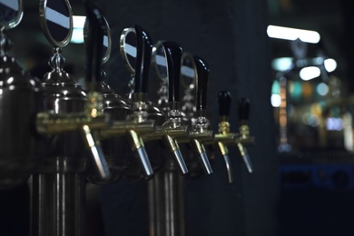 Photo of New modern beer taps on bar counter in pub
