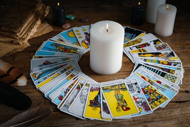 Photo of Burning candle surrounded by tarot cards on wooden table