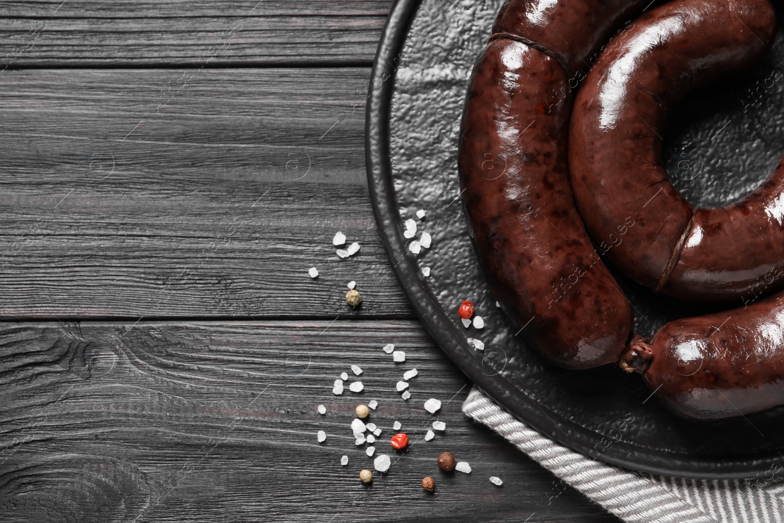 Photo of Tasty blood sausages served on black wooden table, flat lay. Space for text