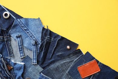 Photo of Flat lay composition with patches of old jeans on yellow background. Space for text