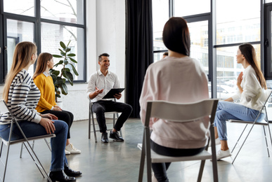 Photo of Psychotherapist working with patients in group therapy session indoors