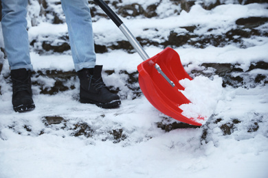 Photo of Man cleaning stairs from snow with shovel outdoors on winter day, closeup