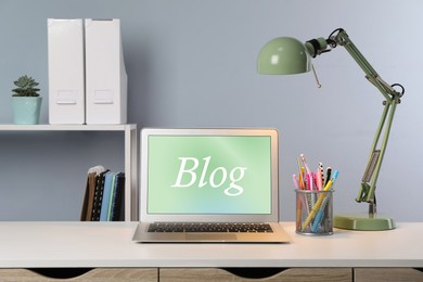 Image of Blogger's workplace with laptop on white table indoors