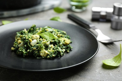 Plate with tasty spinach on grey table, closeup. Healthy food