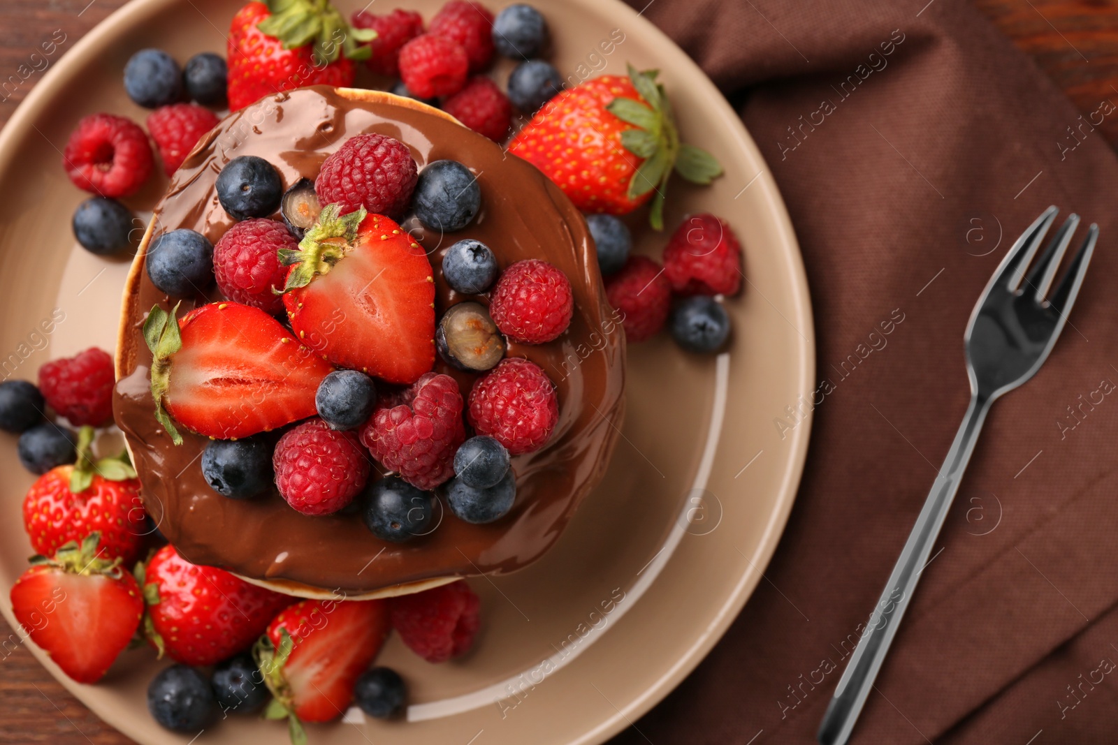 Photo of Stack of tasty pancakes with fresh berries and chocolate spread on table, flat lay