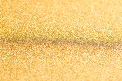 Photo of Beautiful golden shiny glitter as background, closeup