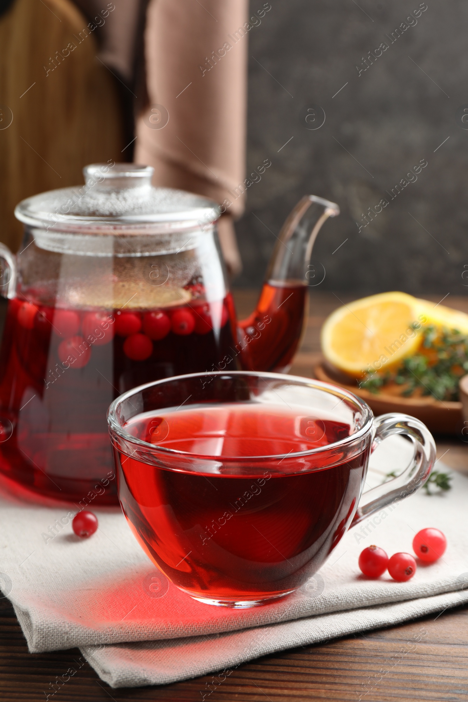 Photo of Tasty hot cranberry tea and fresh berries on wooden table