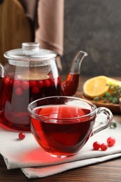 Photo of Tasty hot cranberry tea and fresh berries on wooden table