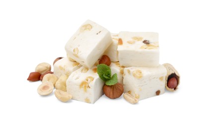 Photo of Pieces of delicious nougat, nuts and mint on white background