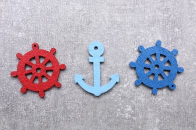 Anchor and ship wheel figures on light grey table, flat lay