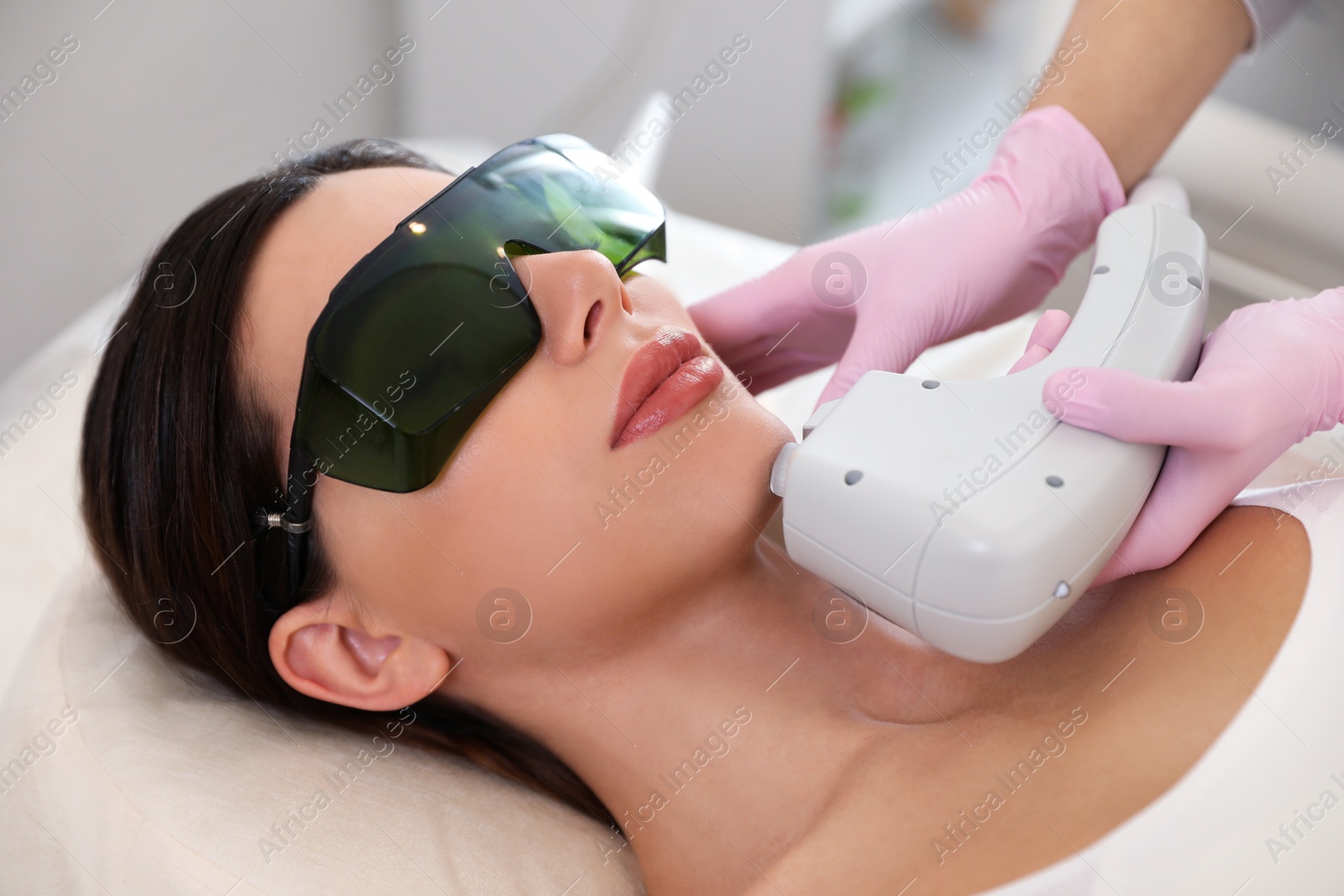 Photo of Young woman undergoing laser epilation procedure in beauty salon