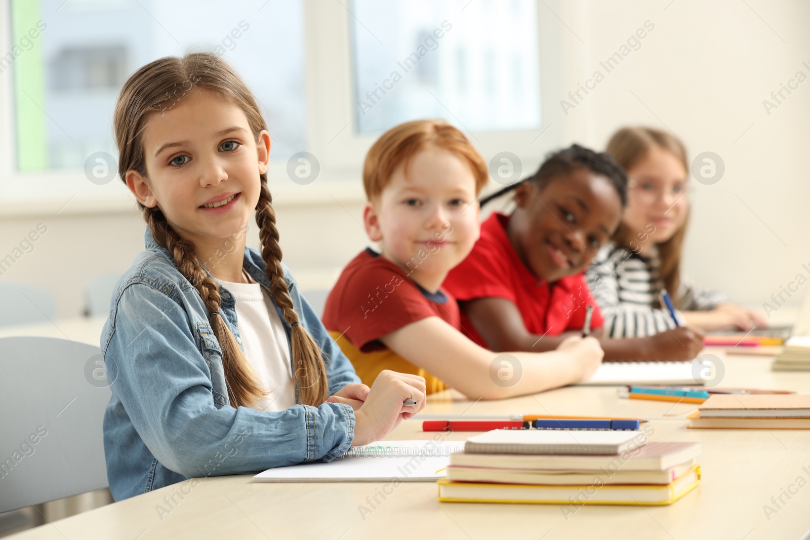 Photo of Smiling girl with her classmates studying in classroom at school