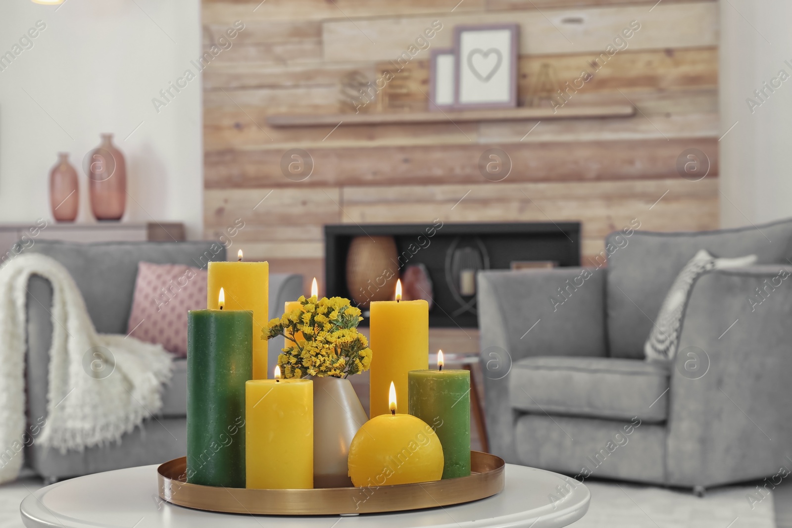 Photo of Tray with burning candles on table in living room