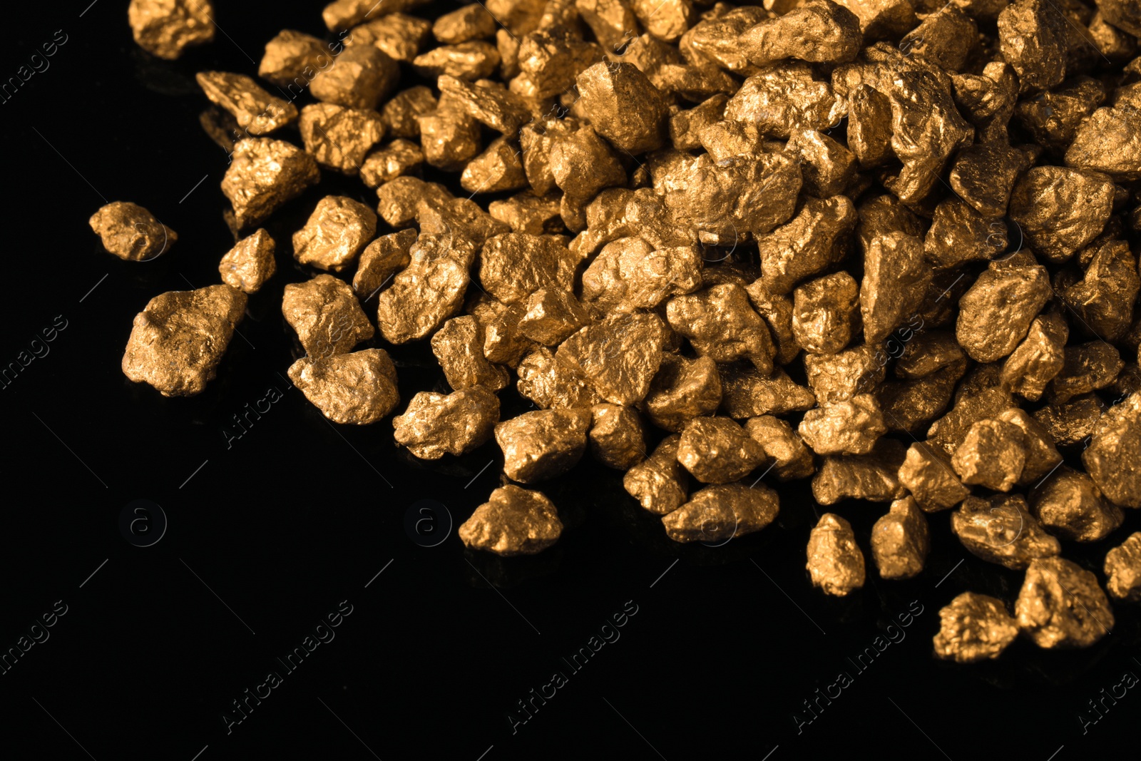 Photo of Pile of gold nuggets on black background, closeup