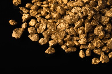 Photo of Pile of gold nuggets on black background, closeup