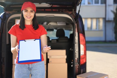 Photo of Courier with clipboard near delivery van outdoors, space for text